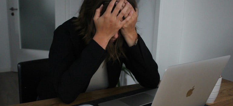 an upset woman looking at a laptop screen.